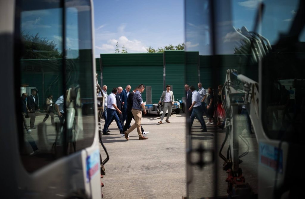 Blick durch Maschinenrahmen auf die Besuchergruppe rund um Kanzler Stocker beim Firmenrundgang
